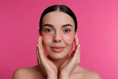 Photo of Beautiful young woman with under eye patches on pink background