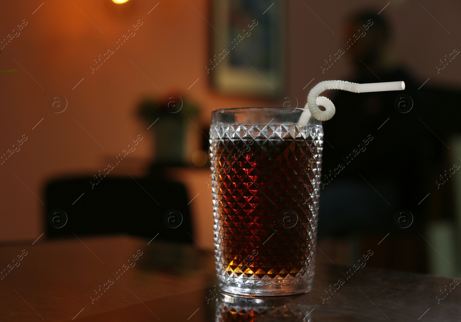 Photo of Glass of cola on table in dark room