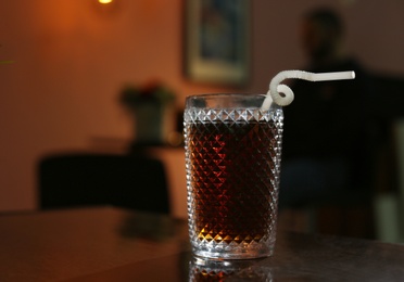 Photo of Glass of cola on table in dark room