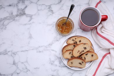 Photo of Sweet hard chuck crackers with raisins, jam and cup of tea on white marble table, flat lay. Space for text