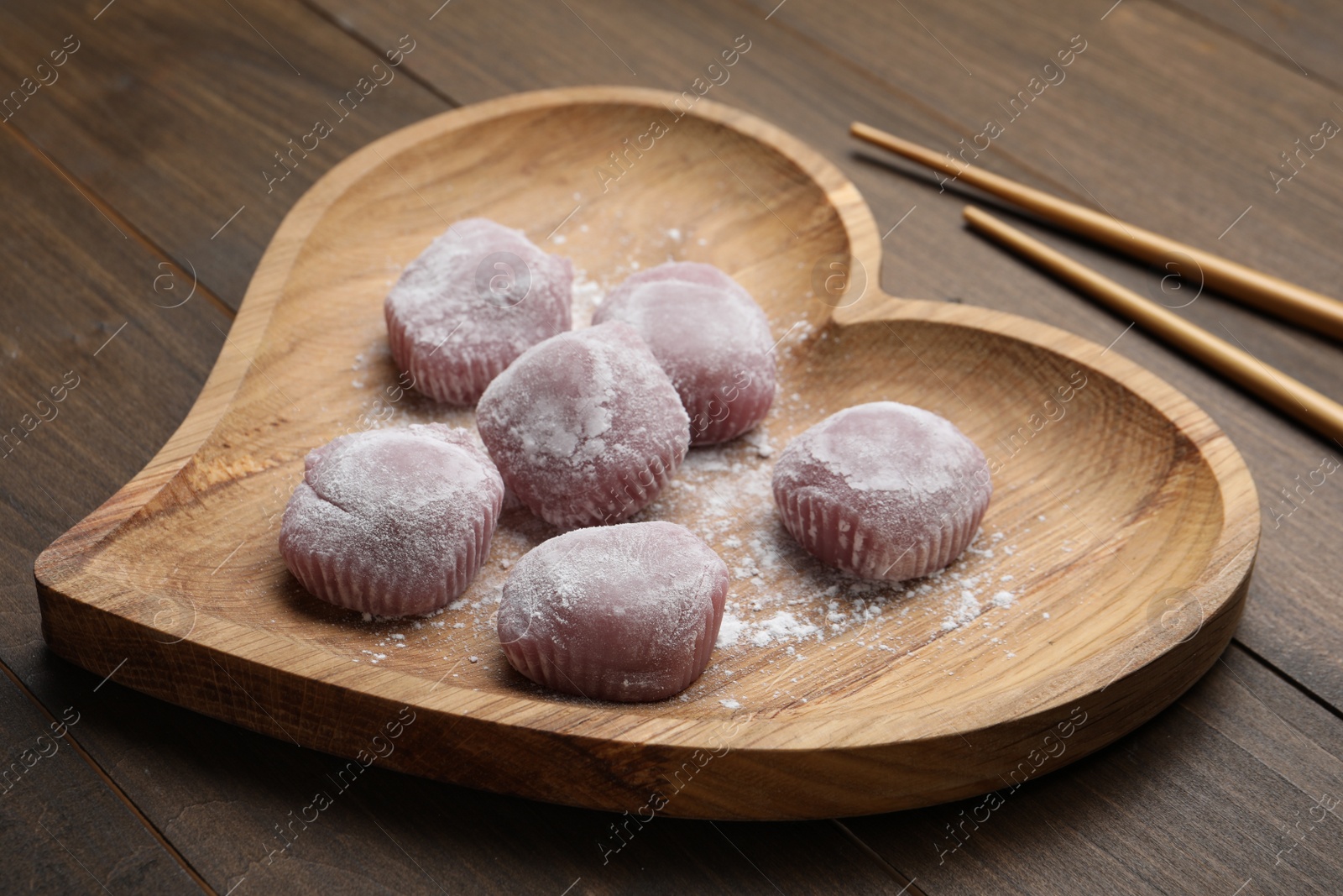 Photo of Heart shaped plate with delicious mochi and chopsticks on wooden table. Traditional Japanese dessert