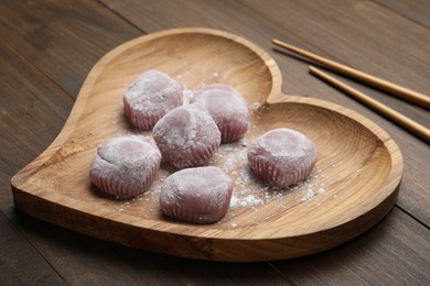 Photo of Heart shaped plate with delicious mochi and chopsticks on wooden table. Traditional Japanese dessert