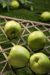 Many fresh green apples on rattan grid