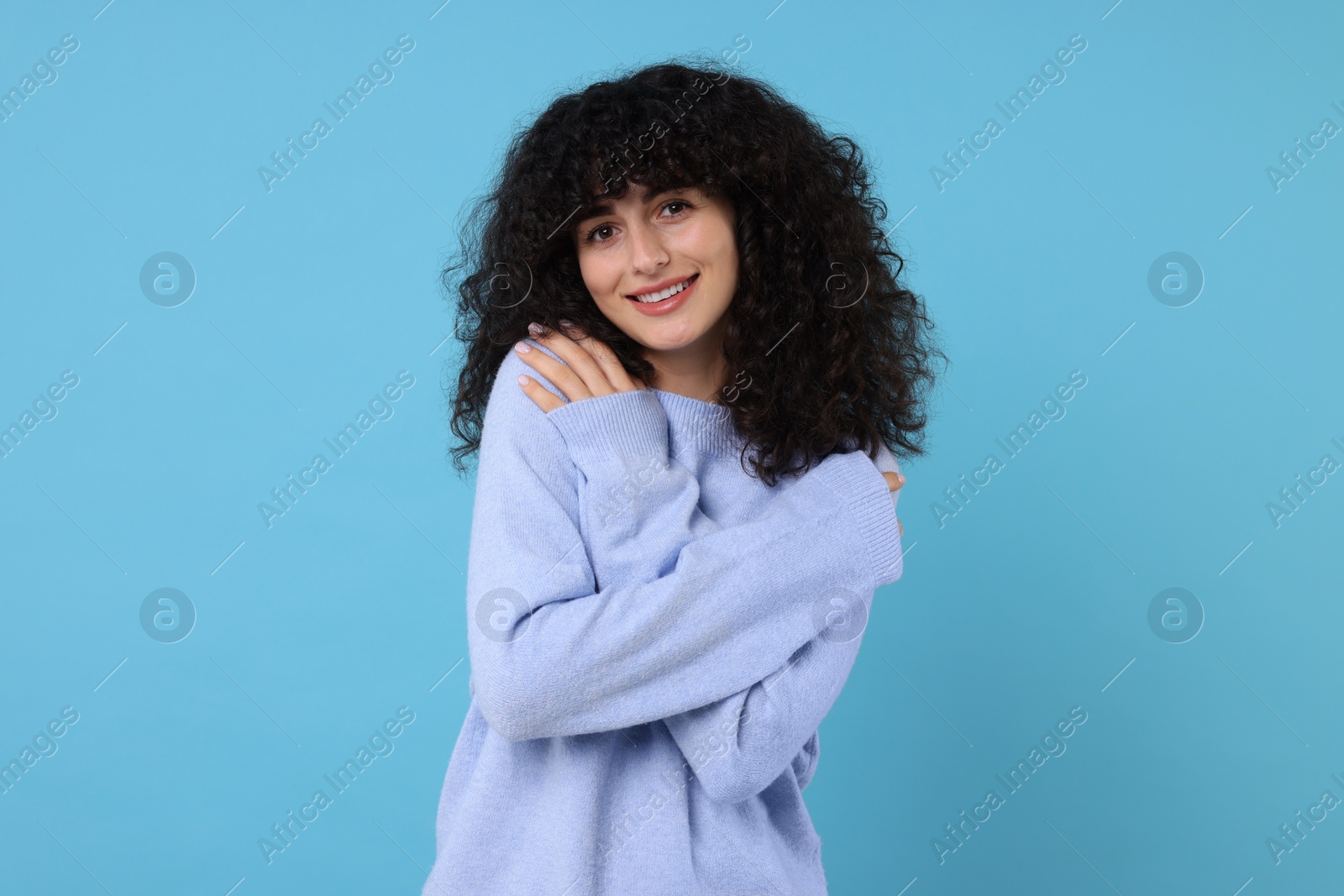 Photo of Happy young woman in stylish warm sweater on light blue background