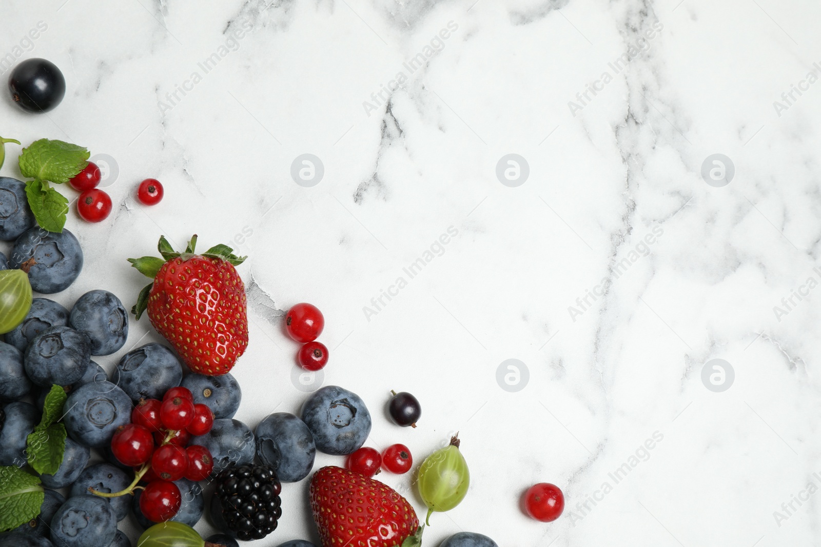 Photo of Mix of fresh berries on white marble table, flat lay. Space for text