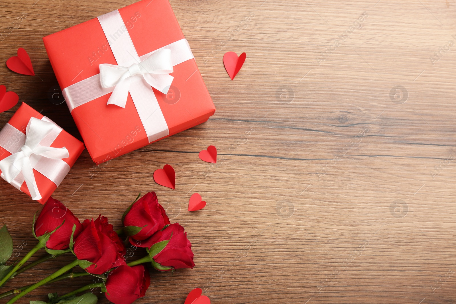 Photo of Gift boxes, roses and paper hearts on wooden background, flat lay with space for text. Valentine's Day celebration