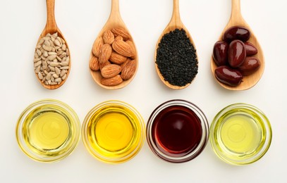 Vegetable fats. Different cooking oils in bowls and spoons with ingredients on white background, flat lay