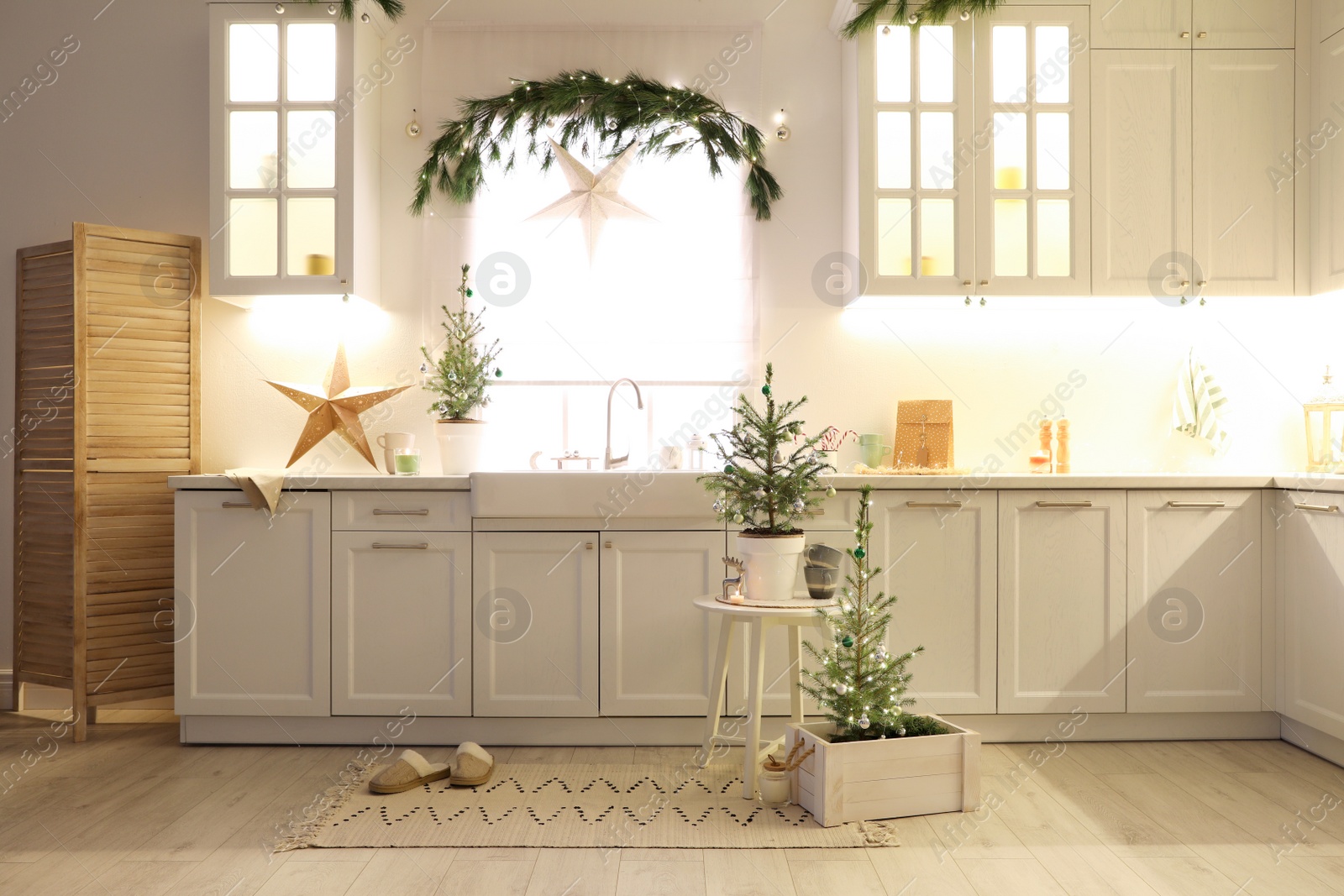 Photo of Small Christmas trees and festive decor in kitchen