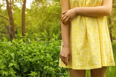 Young woman scratching hand outdoors, space for text. Seasonal allergy