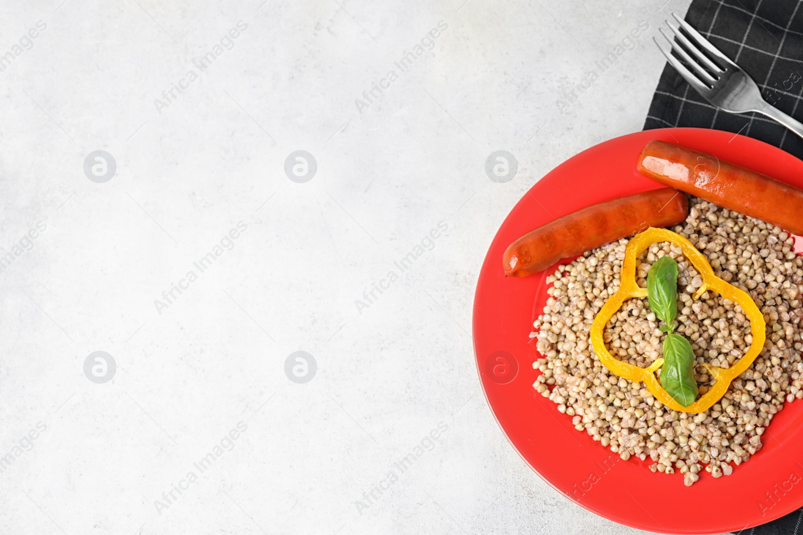 Photo of Tasty buckwheat porridge with sausages on light table, top view. Space for text