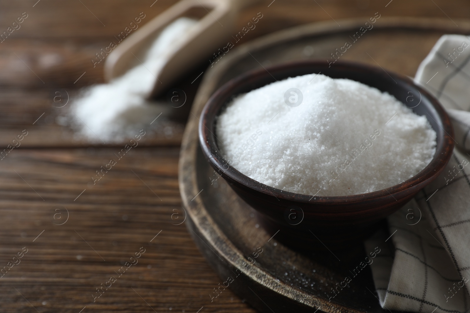 Photo of Organic salt in bowl on wooden table, closeup. Space for text