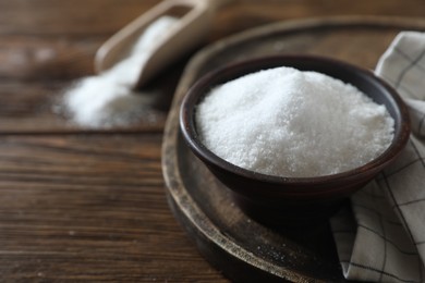 Photo of Organic salt in bowl on wooden table, closeup. Space for text