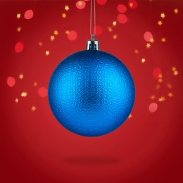 Image of Beautiful blue Christmas ball hanging on red background