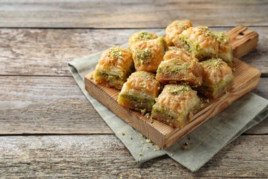 Delicious fresh baklava with chopped nuts on wooden table, space for text Eastern sweets