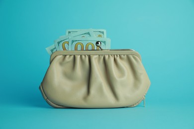 One stylish leather purse with money on light blue background