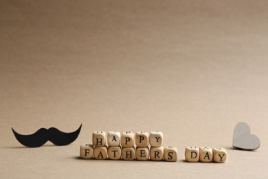 Photo of Words HAPPY FATHER'S DAY made with wooden cubes on beige background. Space for text