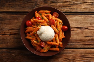 Photo of Delicious pasta with burrata cheese and tomatoes on wooden table, top view