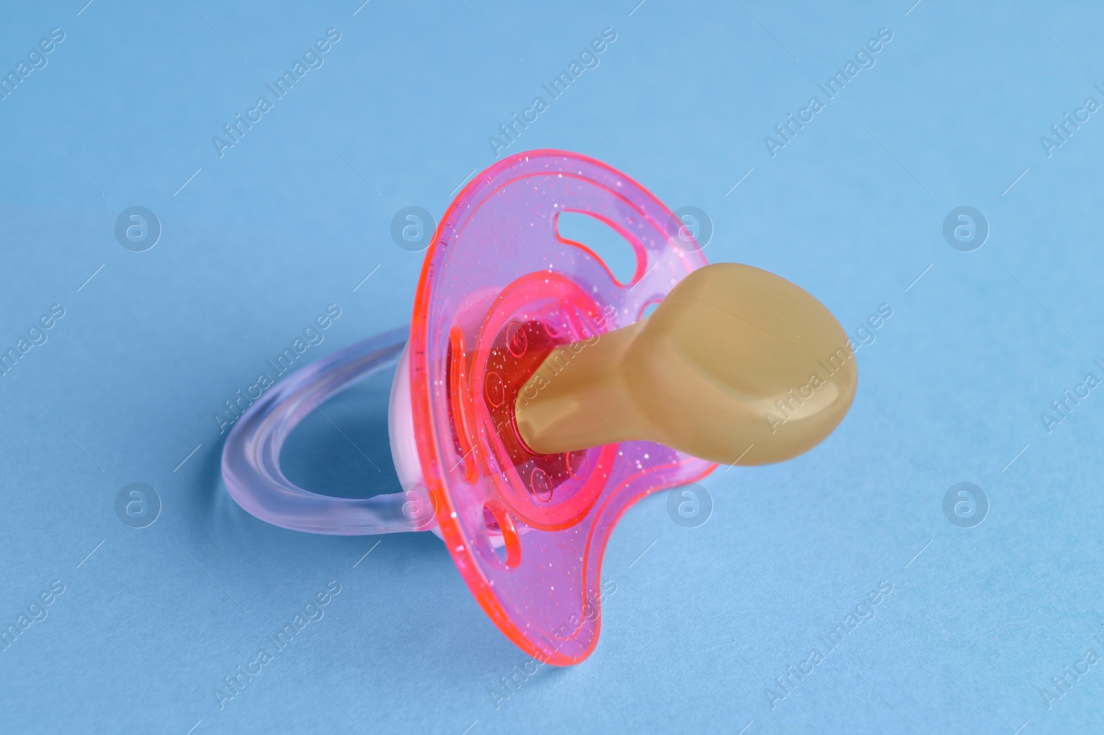 Photo of New baby pacifier on light blue background, closeup