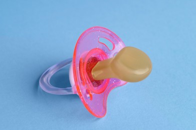 Photo of New baby pacifier on light blue background, closeup