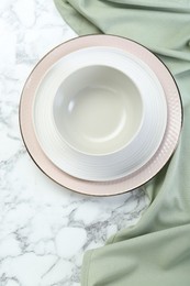 Clean plates and bowl on white marble table, top view