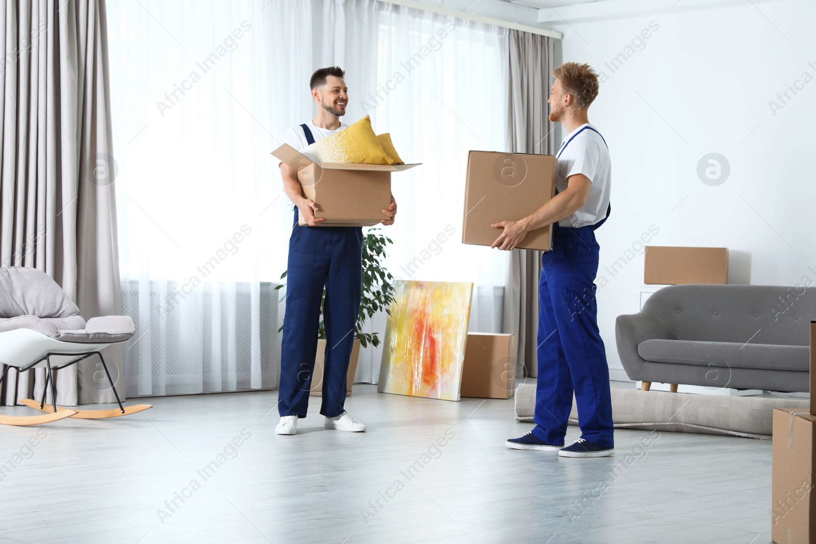 Photo of Moving service employees with cardboard boxes in room