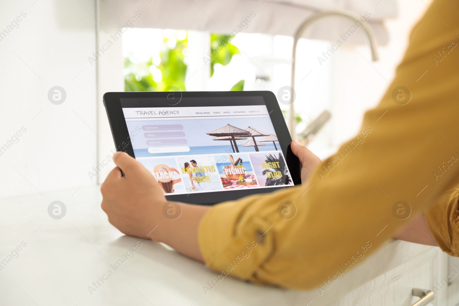 Photo of Young woman using tablet to plan trip indoors, closeup. Travel agency concept