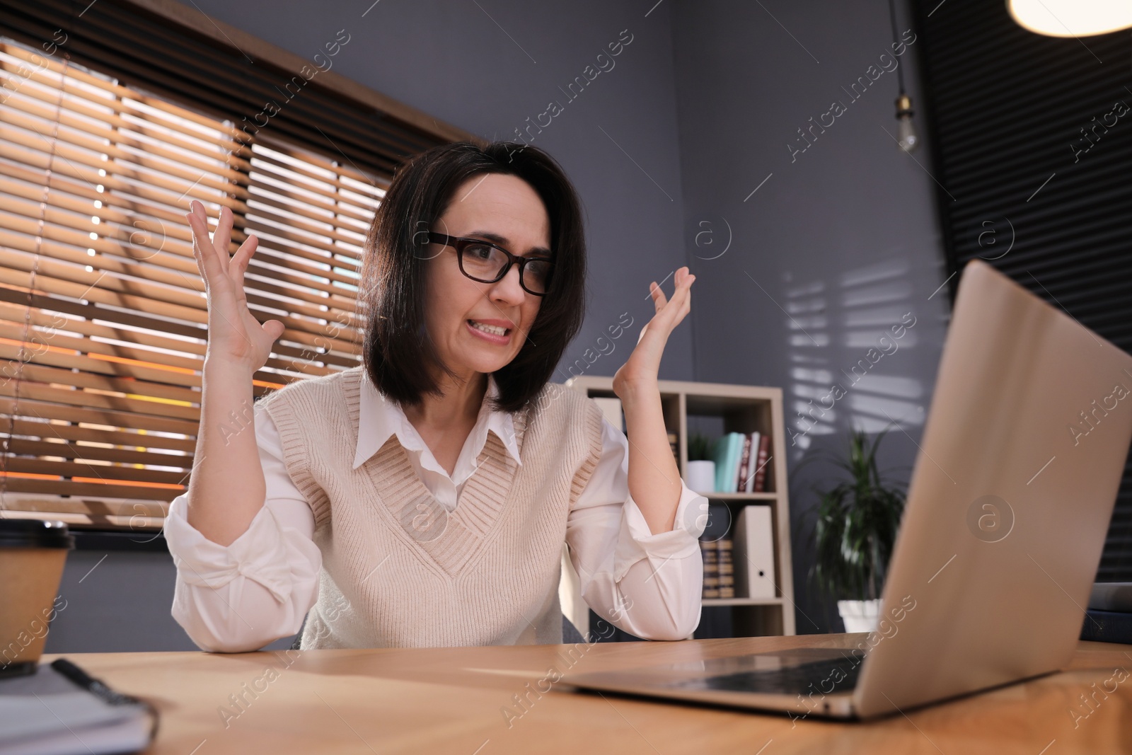 Photo of Emotional businesswoman working on laptop in office. Online hate concept