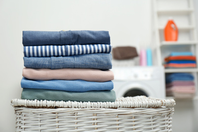 Photo of Stack of fresh laundry on basket in bathroom