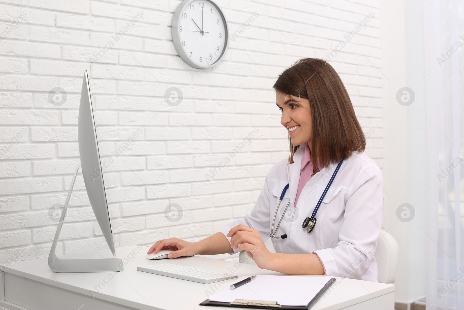 Photo of Pediatrician consulting patient online at table in clinic