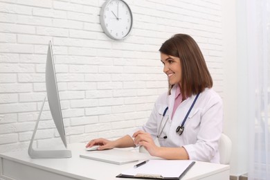 Photo of Pediatrician consulting patient online at table in clinic