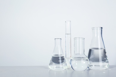 Photo of Laboratory glassware with liquid on table against light background. Chemical analysis