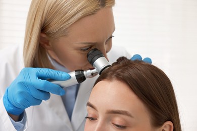 Photo of Trichologist with dermatoscope examining patient`s hair in clinic