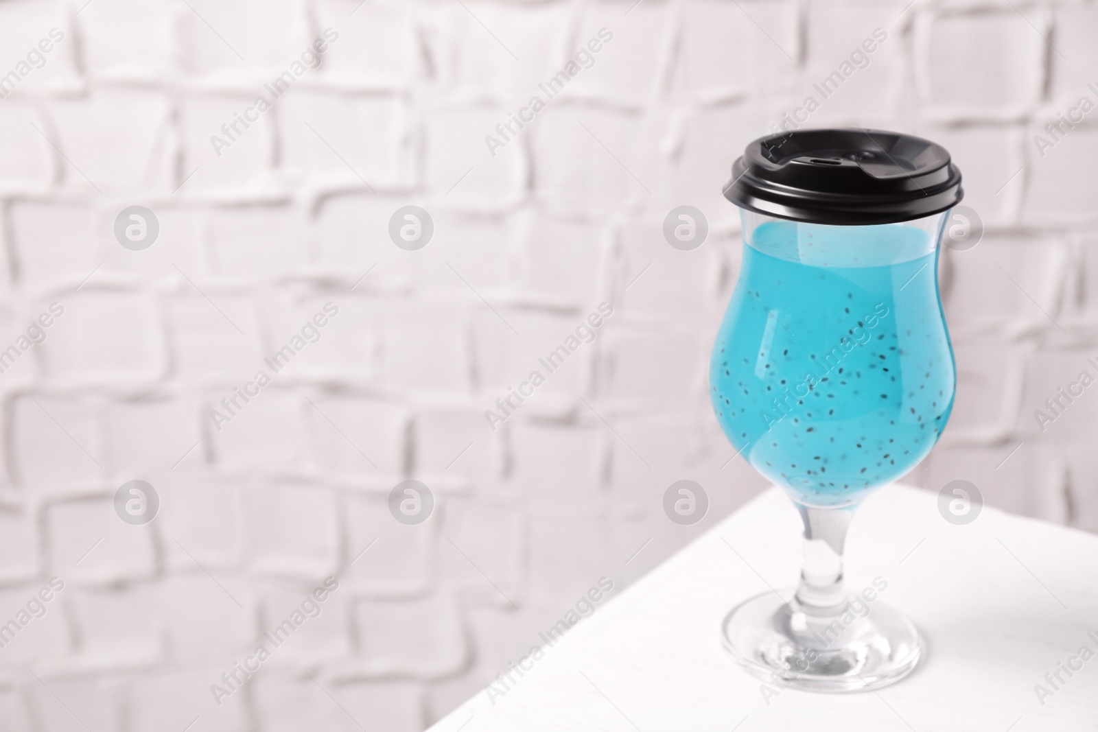 Photo of Light blue drink in glass with lid on white table, space for text