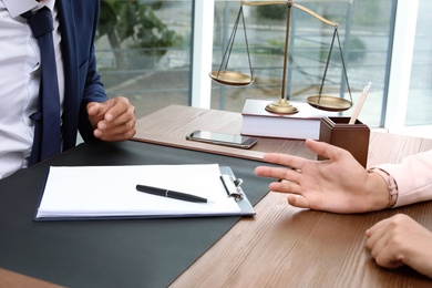 Photo of Male lawyer working with client at table in office