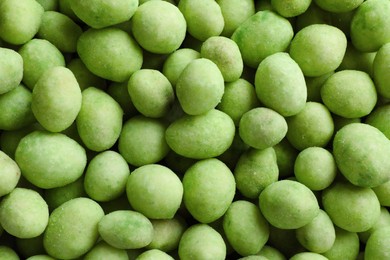 Photo of Tasty wasabi coated peanuts as background, top view