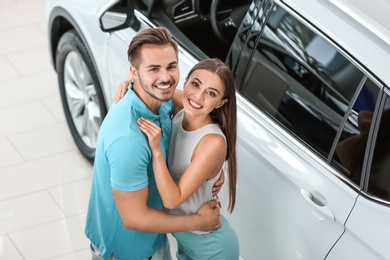 Happy couple buying new car in salon