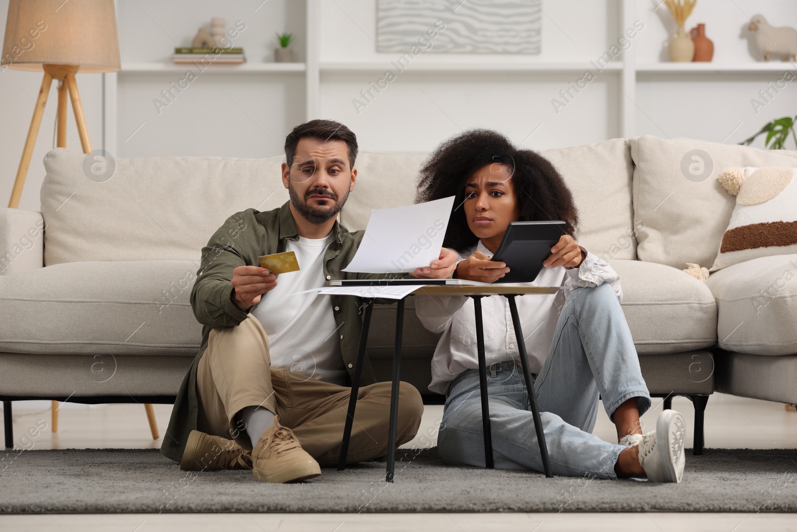 Photo of Confused couple with calculator, credit card and debt notification planning budget at home. Financial problem