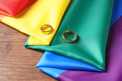 Wedding rings and rainbow flag on wooden table. Gay marriage