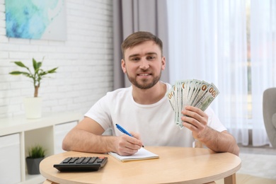 Happy young man with money at home