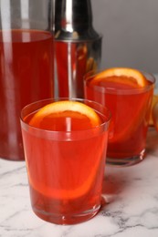 Photo of Aperol spritz cocktail and orange slices in glasses on white marble table, closeup