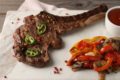 Delicious fried beef meat served with vegetables on marble board, closeup