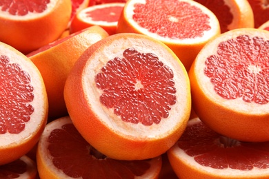 Many sliced fresh ripe grapefruits as background, closeup