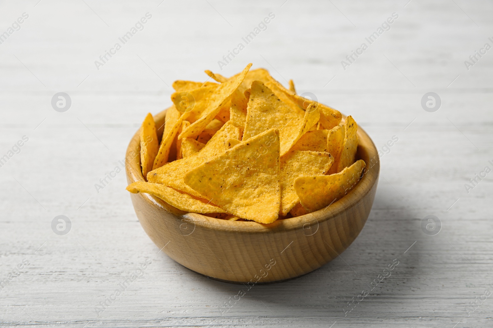 Photo of Tasty mexican nachos chips in bowl on white wooden table