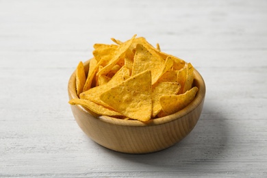 Tasty mexican nachos chips in bowl on white wooden table