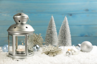 Christmas lantern with burning candle and festive decor on snow