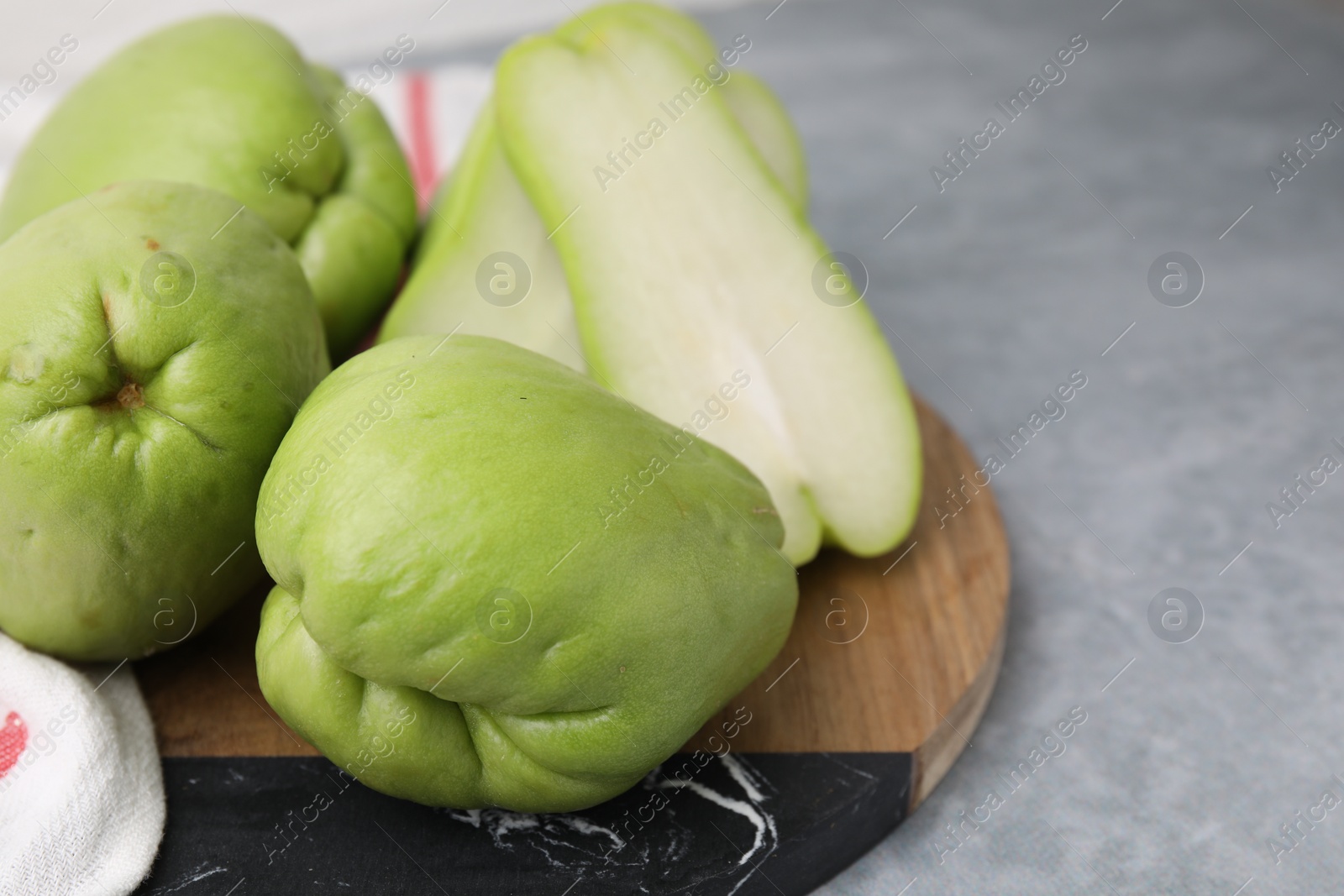 Photo of Cut and whole chayote on gray table, closeup