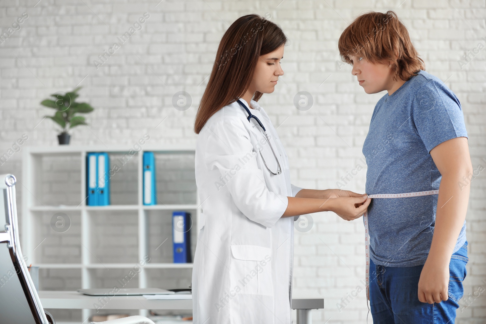 Photo of Female doctor measuring overweight boy in clinic