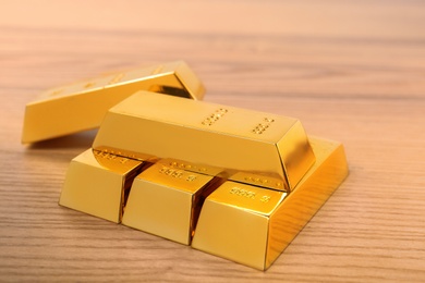 Photo of Stack of shiny gold bars on wooden table