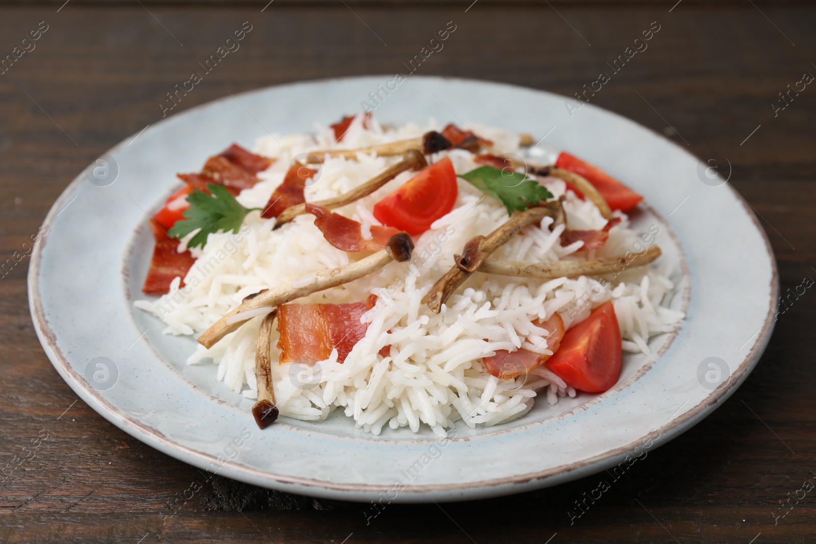 Photo of Delicious rice with bacon, mushrooms and tomatoes on table, closeup