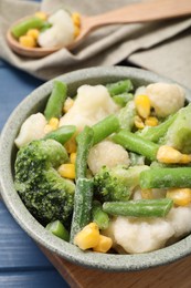 Photo of Mix of different frozen vegetables in bowl on blue wooden table, closeup